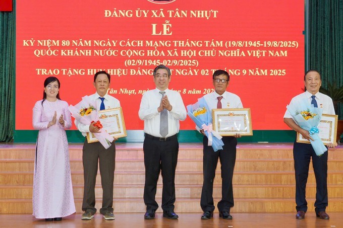 Phó Bí thư Thành ủy TPHCM Nguyễn Phước Lộc cùng lãnh đạo xã Tân Nhựt trao Huy hiệu Đảng. (Ảnh: SGGP)