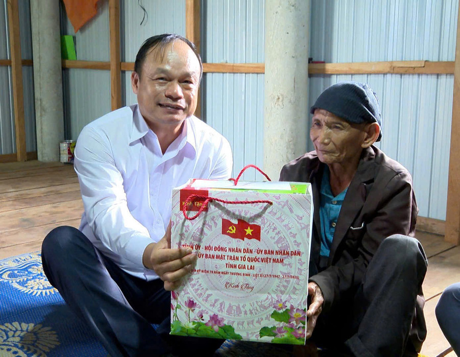 Phó Chủ tịch UBND tỉnh Dương Mah Tiệp (bìa trái) tặng quà cho ông Đinh Văn Phương (người có công với cách mạng, làng Ka Bưng, xã Canh Liên). Ảnh: Nhật Trường