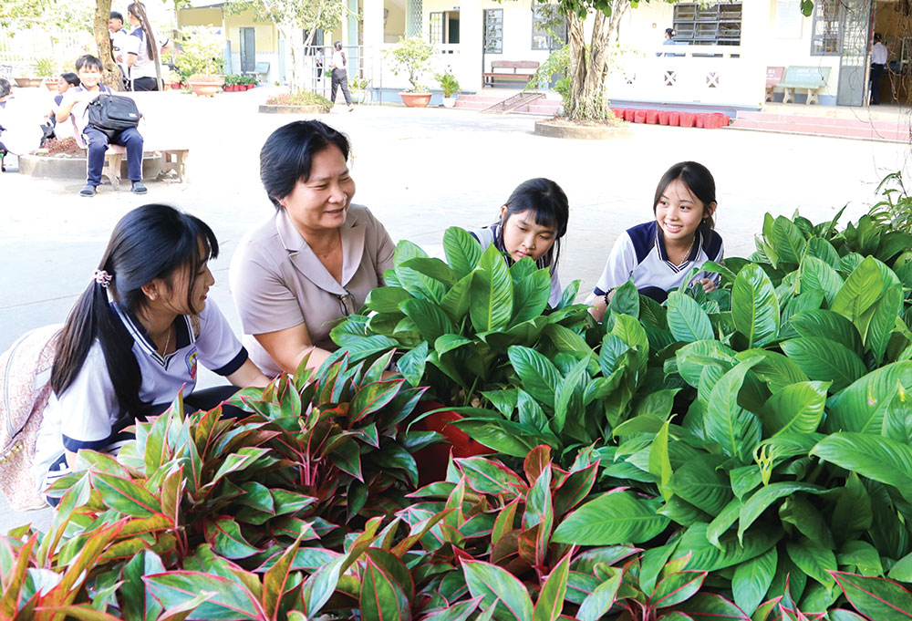 Cô Phạm Hồng Diệu hướng dẫn học sinh chăm sóc kiểng phục vụ Tết. ẢNH: NGỌC XOÀN