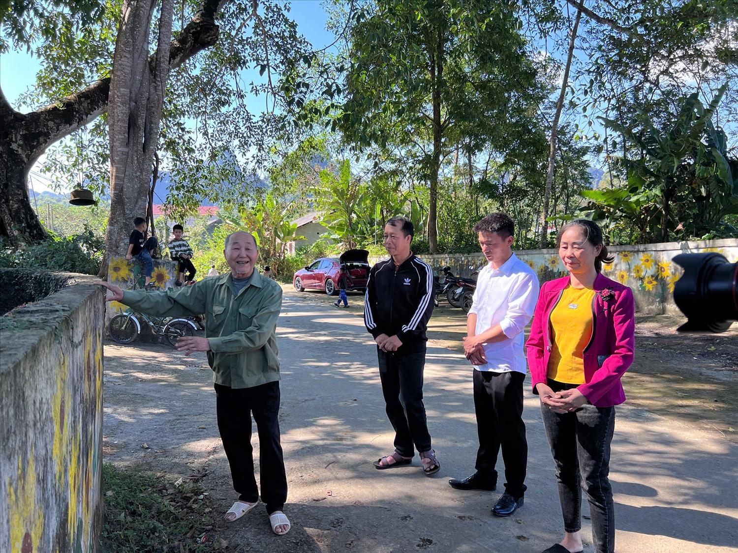 Người có uy tín Triệu Văn Khay (bên trái) trao đổi với người dân trong thôn về làm đường Nông thôn mới