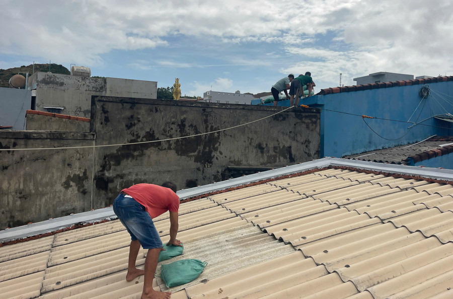 Người dân làng biển Nhơn Lý dùng bao cát dằn mái nhà để tránh gió bão. Ảnh: Ngọc Nhuận chu-dong-giang-chong-nha-cuajpg.jpg