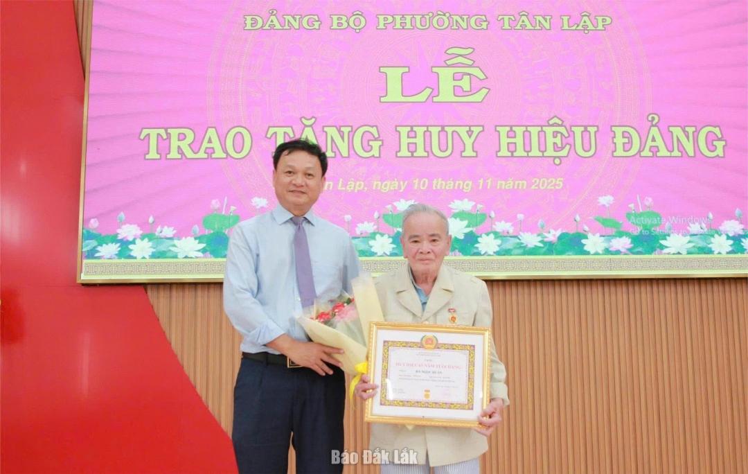 Bí thư Đảng ủy, Chủ tịch HĐND phường Tân Lập Vũ Văn Hưng trao Huy hiệu 65 năm tuổi Đảng cho đảng viên.