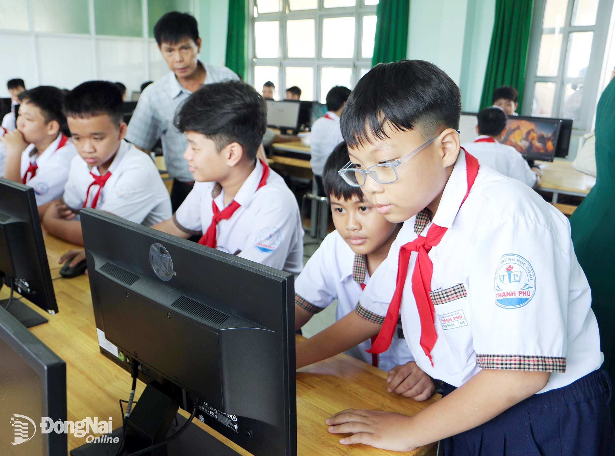 Em Lê Phát Đạt (học sinh Trường THCS Thạnh Phú, phường Tân Triều) hướng dẫn bạn sử dụng máy vi tính. Ảnh: Văn Truyên