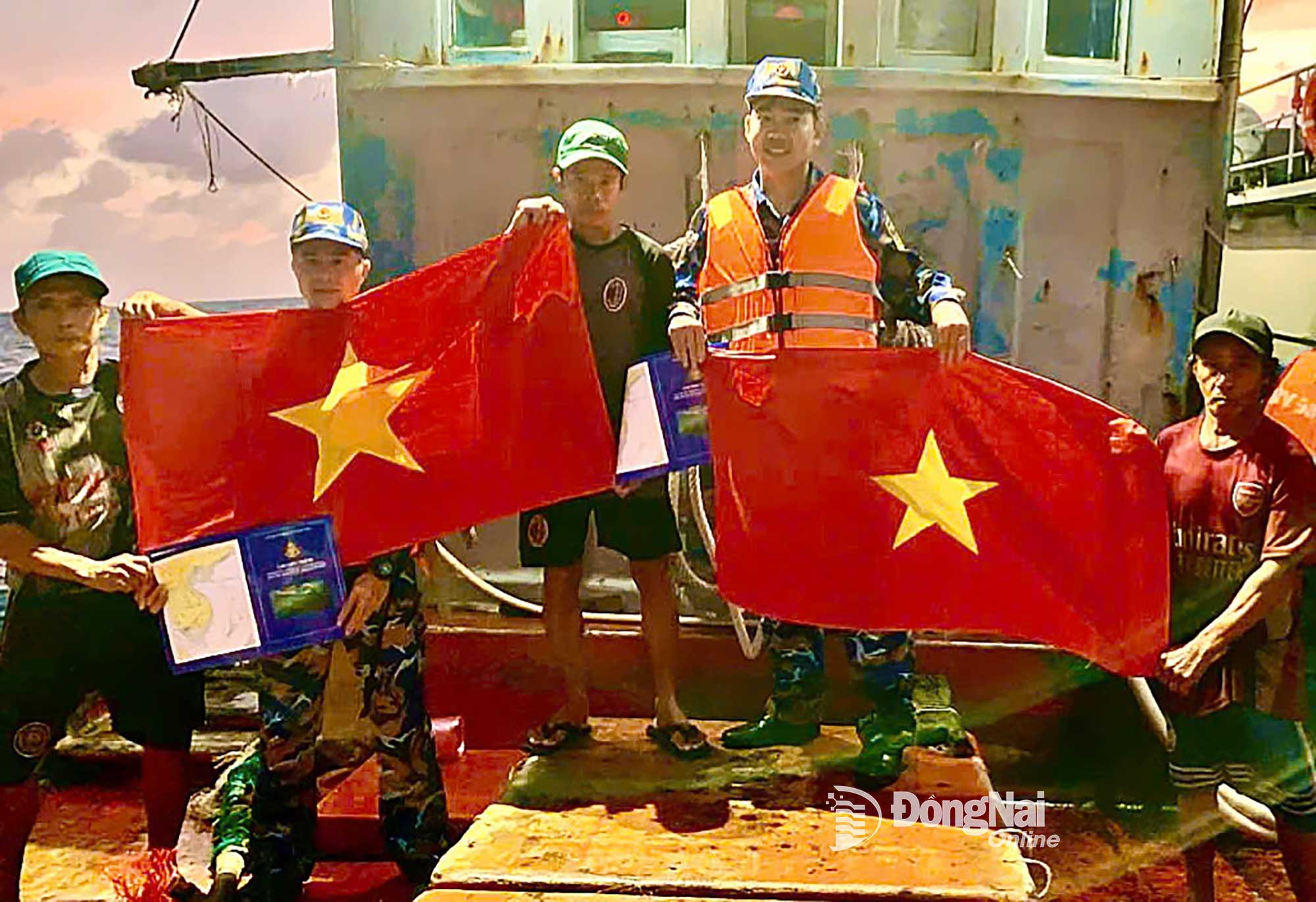 6. C&aacute;n bộ, chiến sĩ V&ugrave;ng 2 Hải qu&acirc;n tuy&ecirc;n truyền v&agrave; tặng cờ Tổ quốc cho c&aacute;c ngư d&acirc;n tr&ecirc;n biển. Ảnh: Văn Đường