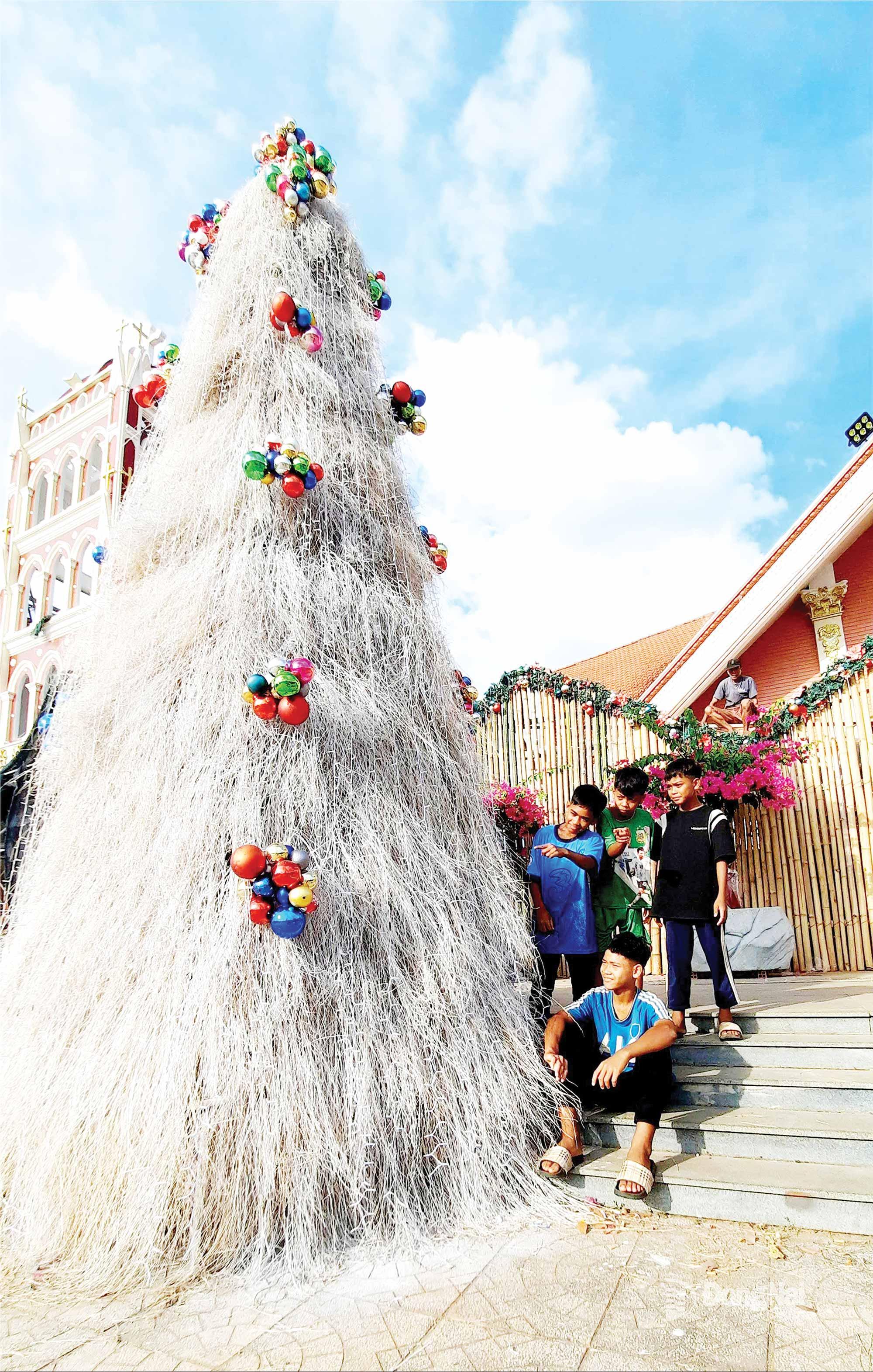 C&acirc;y th&ocirc;ng Gi&aacute;ng sinh cao gần 10m được kết bằng cỏ tại gi&aacute;o xứ An Khương (x&atilde; T&acirc;n Hưng). Ảnh: Văn Truy&ecirc;n    