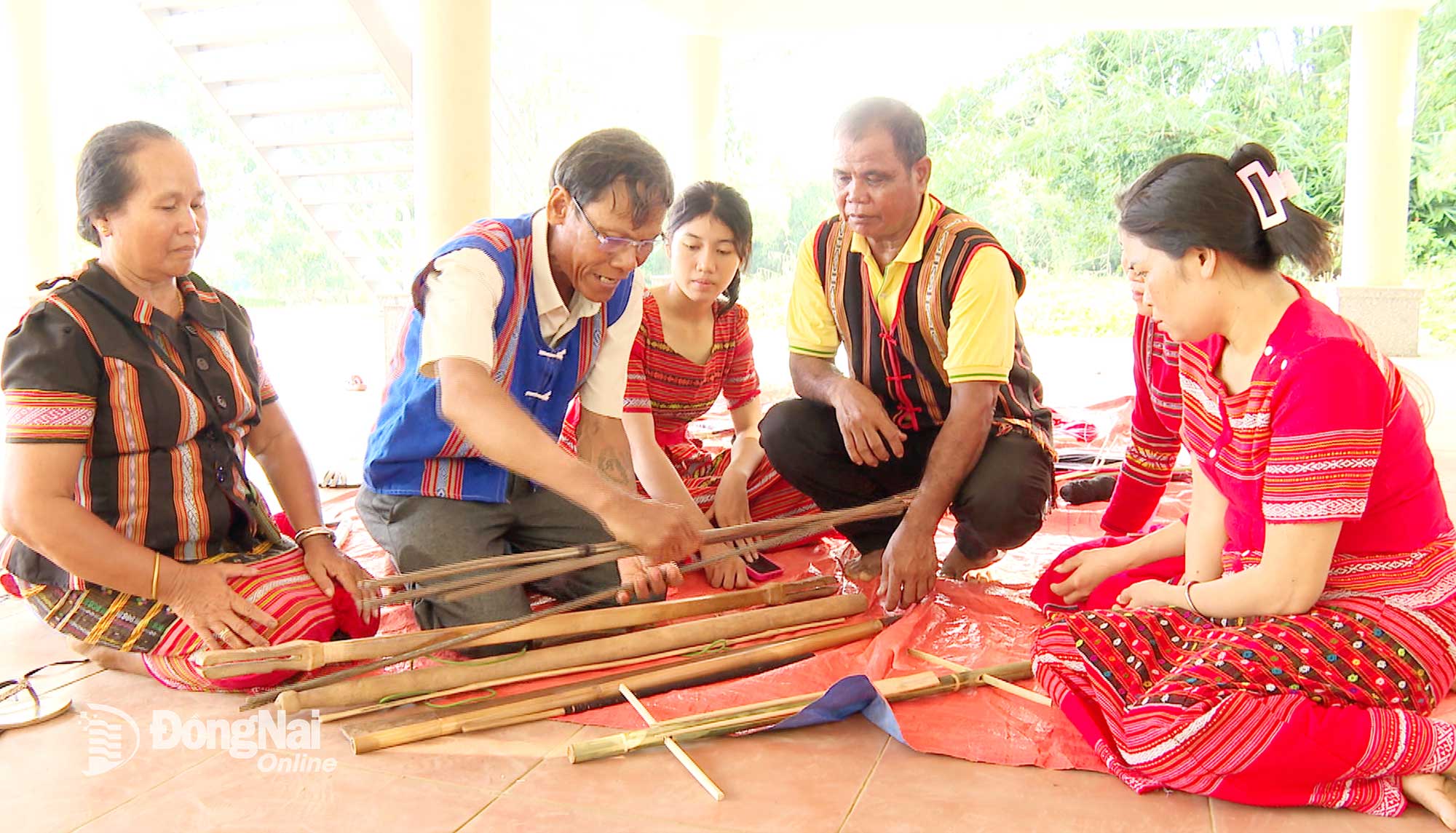 Ông Điểu Sơn Ray (thứ 2 từ trái qua) hướng dẫn bà con sử dụng khung dệt để tạo ra hoa văn trên tấm thổ cẩm. Ảnh: Từ Huy