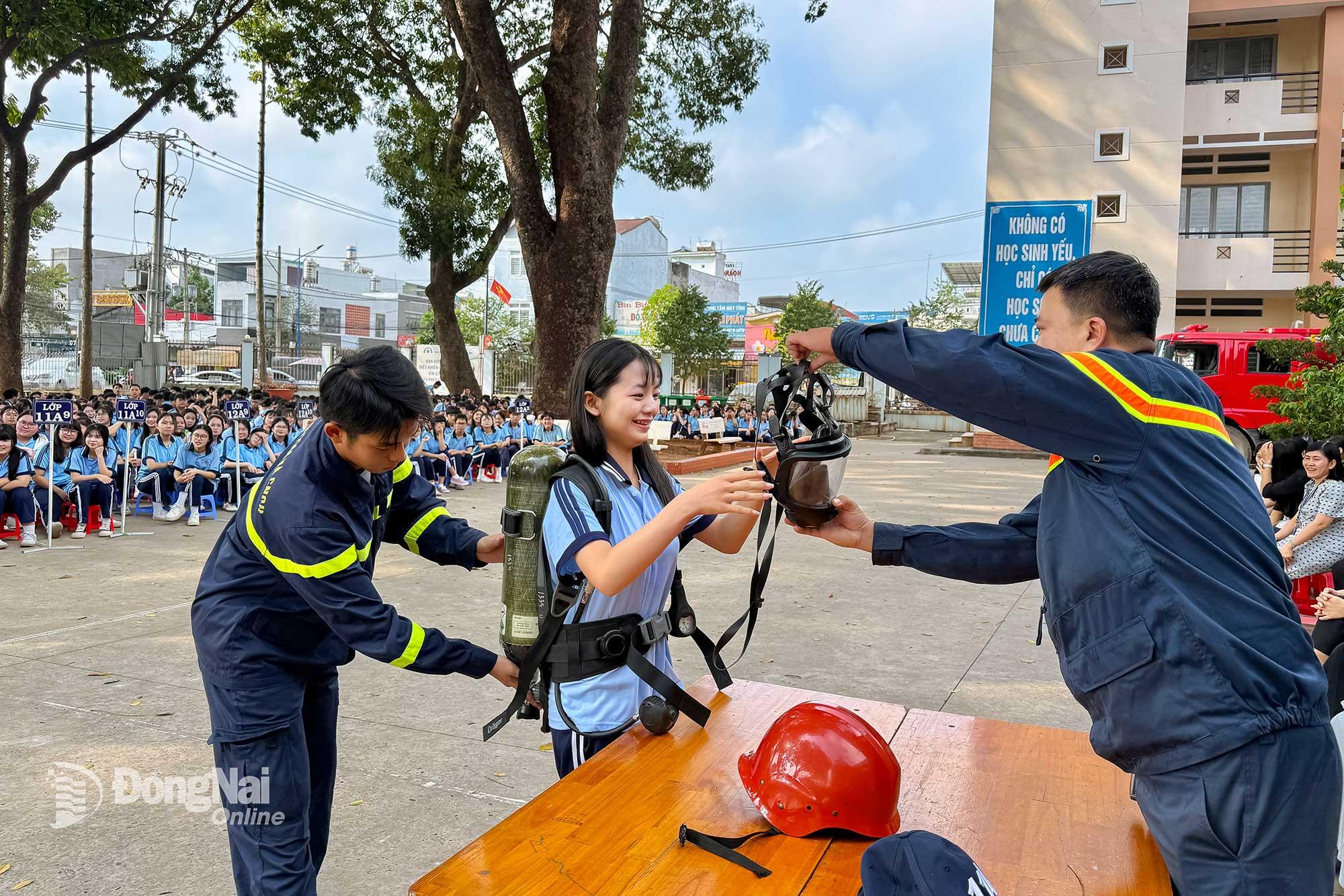 Học sinh Trường THPT Nguyễn Đ&igrave;nh Chiểu (x&atilde; Long Th&agrave;nh) được trải nghiệm sử dụng bộ b&igrave;nh kh&iacute;, mặt nạ cứu nạn chuy&ecirc;n dụng. Ảnh: Đăng T&ugrave;ng