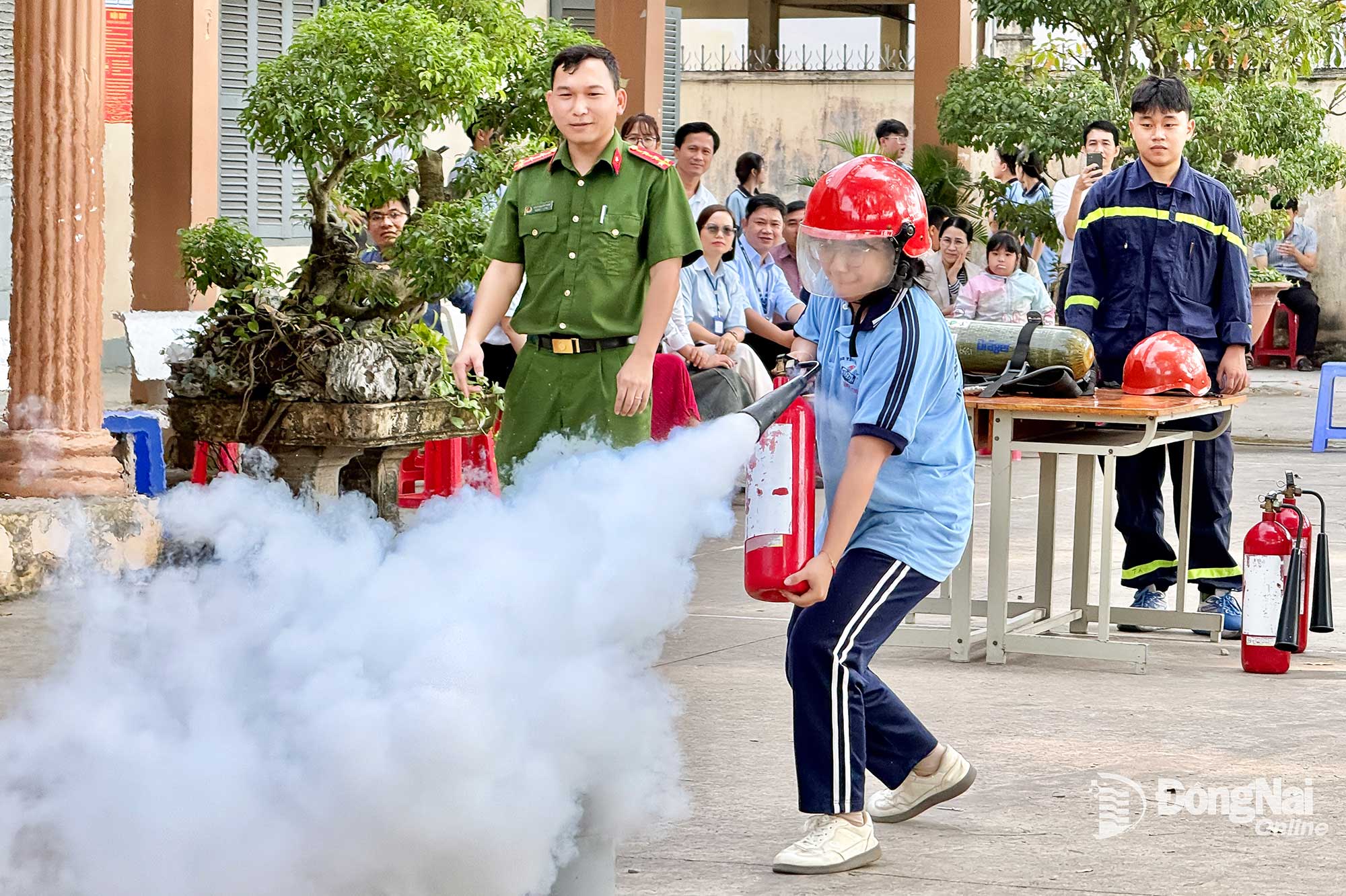 Học sinh Trường THPT Nguyễn Đ&igrave;nh Chiểu (x&atilde; Long Th&agrave;nh) được thực h&agrave;nh dập tắt đ&aacute;m ch&aacute;y kh&iacute; gas bằng b&igrave;nh chữa ch&aacute;y x&aacute;ch tay. Ảnh: Đăng T&ugrave;ng