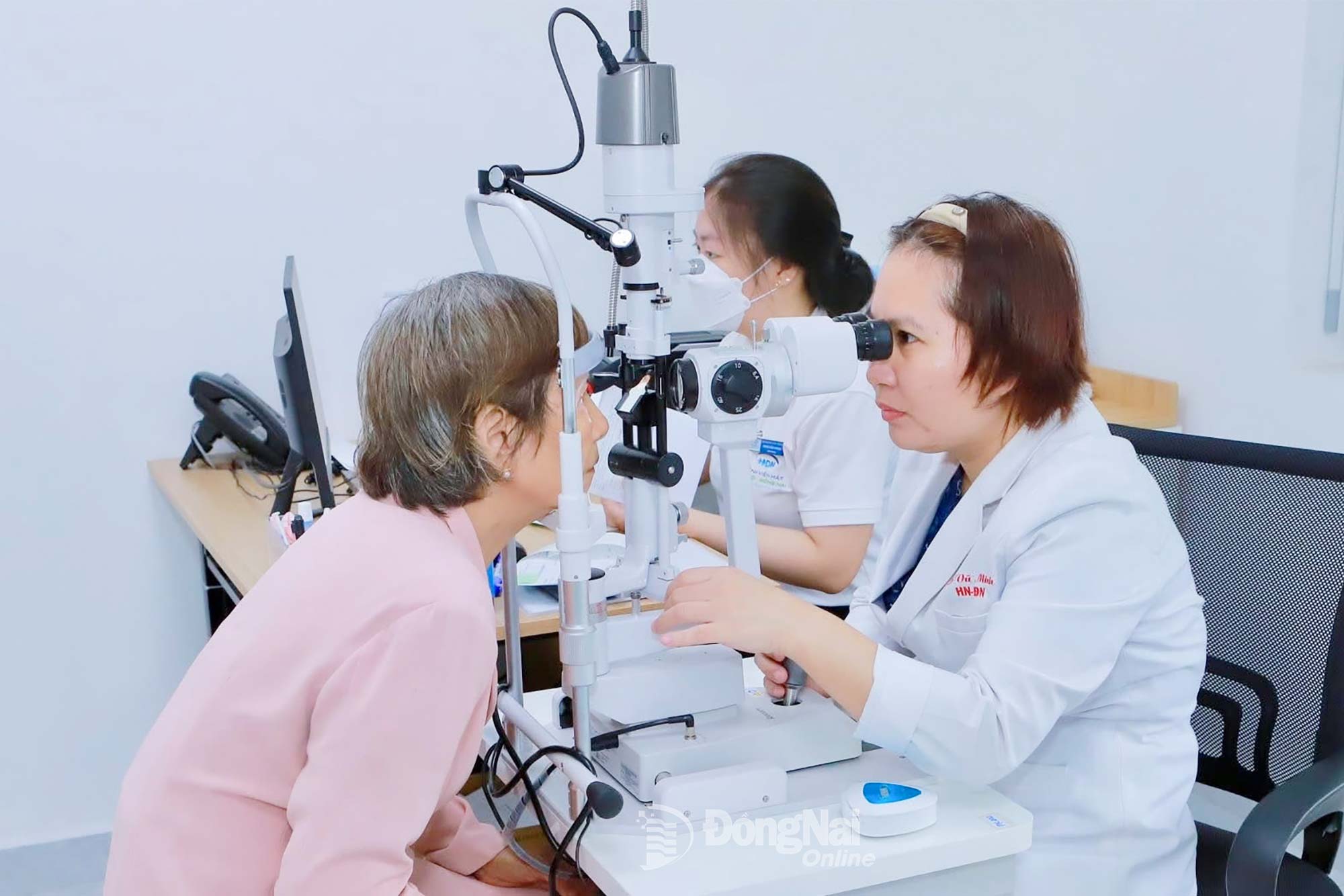 Bác sĩ Vũ Thị Minh, Bệnh viện Mắt Hà Nội - Đồng Nai (phường Tam Hiệp) khám mắt, đánh giá tình trạng nếp nhăn đuôi mắt cho một bệnh nhân.