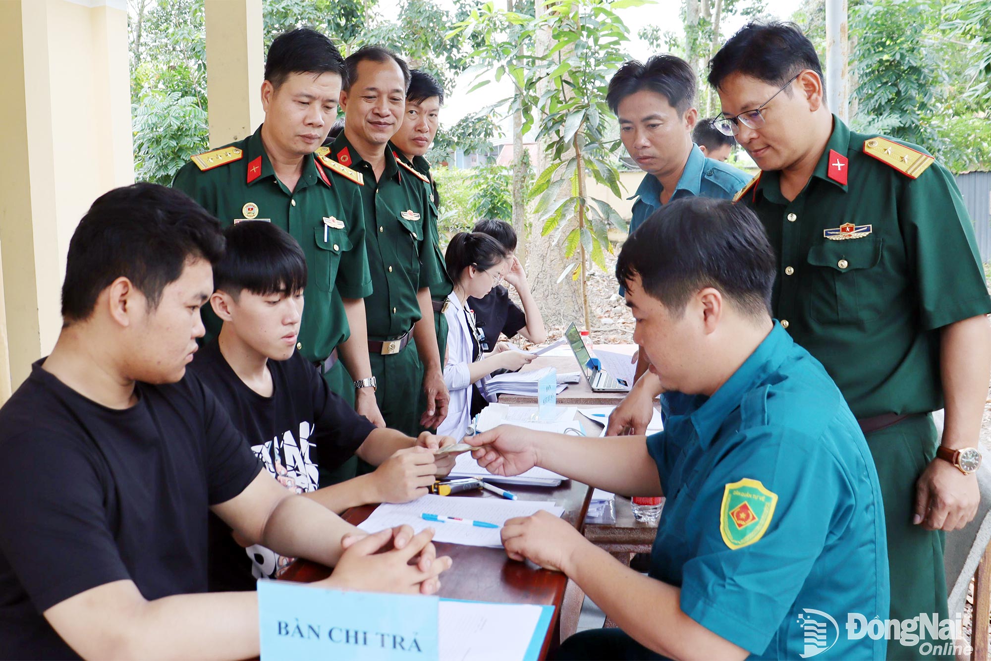 Trung tá Hoàng Mạnh Chính (bìa phải), Trưởng đoàn kiểm tra của Bộ Chỉ huy Quân sự tỉnh giám sát công tác chi trả chế độ cho thanh niên đến khám tuyển tại xã Đồng Phú.“