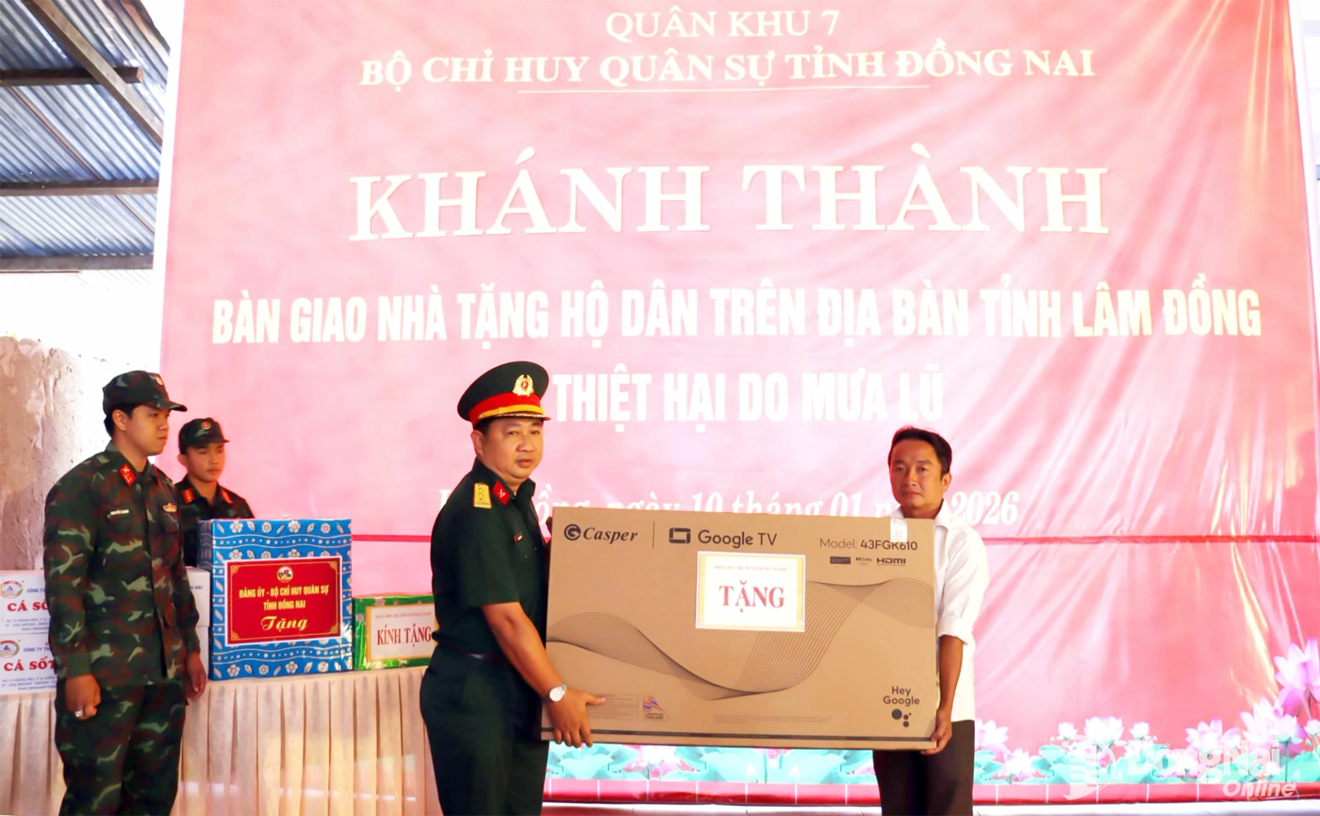 Thượng tá Nguyễn Minh Hiếu, Phó Trưởng phòng Doanh trại, Cục Hậu cần - Kỹ thuật Quân khu 7 trao ảnh Bác, cờ Tổ quốc và tặng quà cho gia đình người dân bị ảnh hưởng thiên tai. Ảnh: Nguyệt Hà