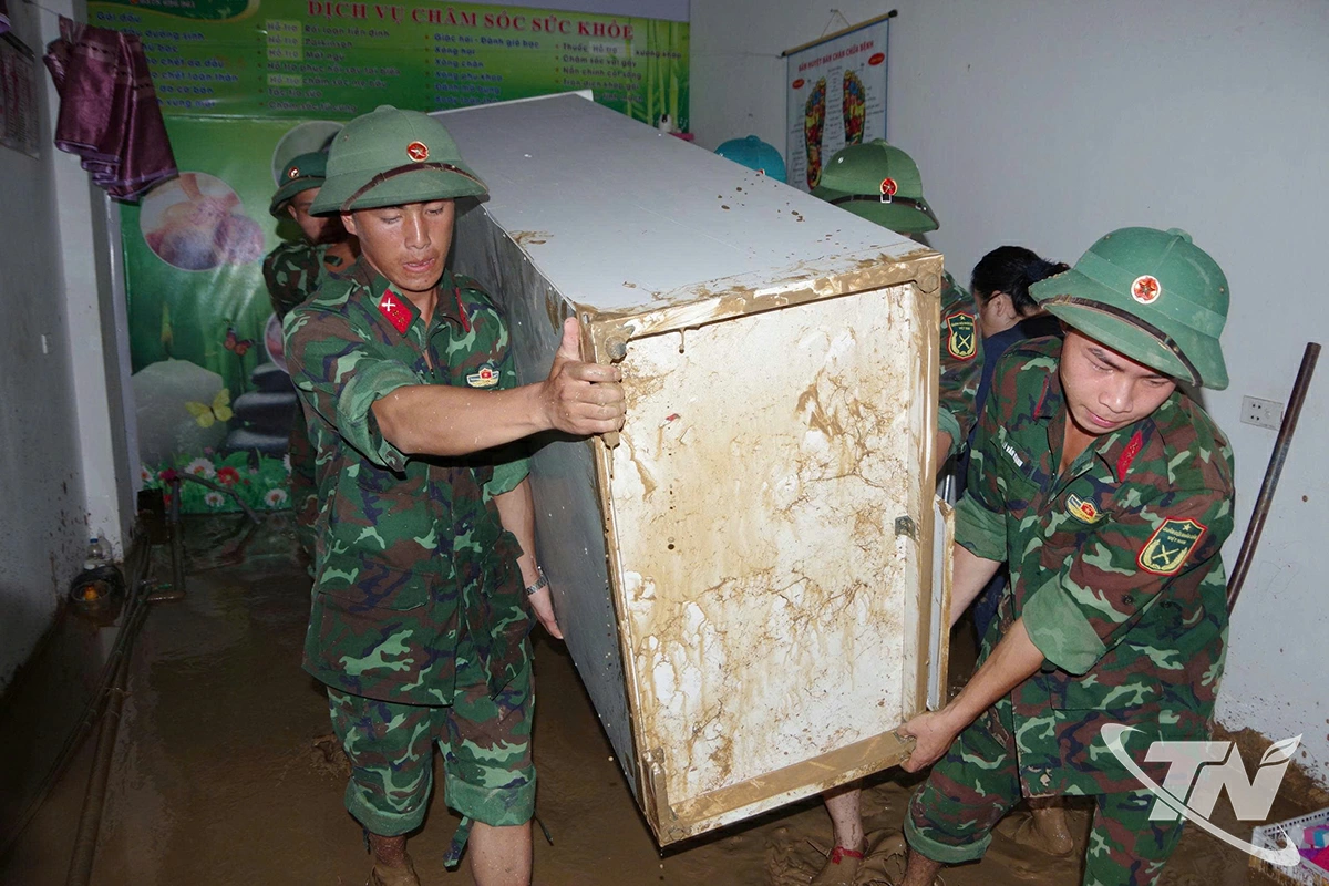 Cán bộ, chiến sĩ Trung đoàn 750 giúp gia đình bà Ma Thị Phương Anh vận chuyển vật dụng, dọn dẹp bùn đất.