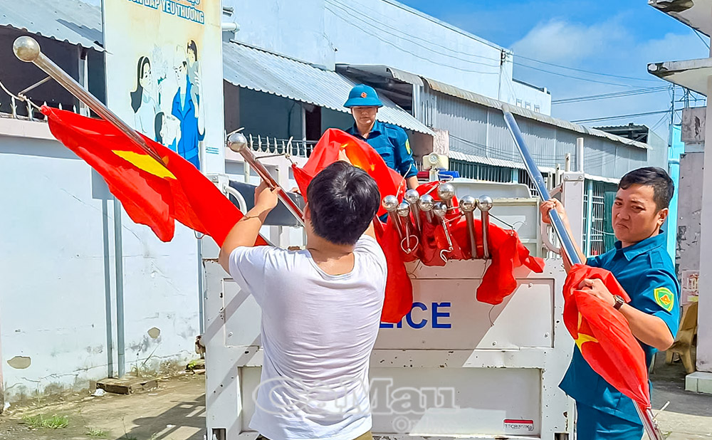 HB1: Trung tâm Văn hoá - Thể thao và Truyền thông xã chuẩn bị cờ Tổ quốc để treo trên tuyến từ Cầu Sập đến ấp An Khoa, xã Vĩnh Mỹ.