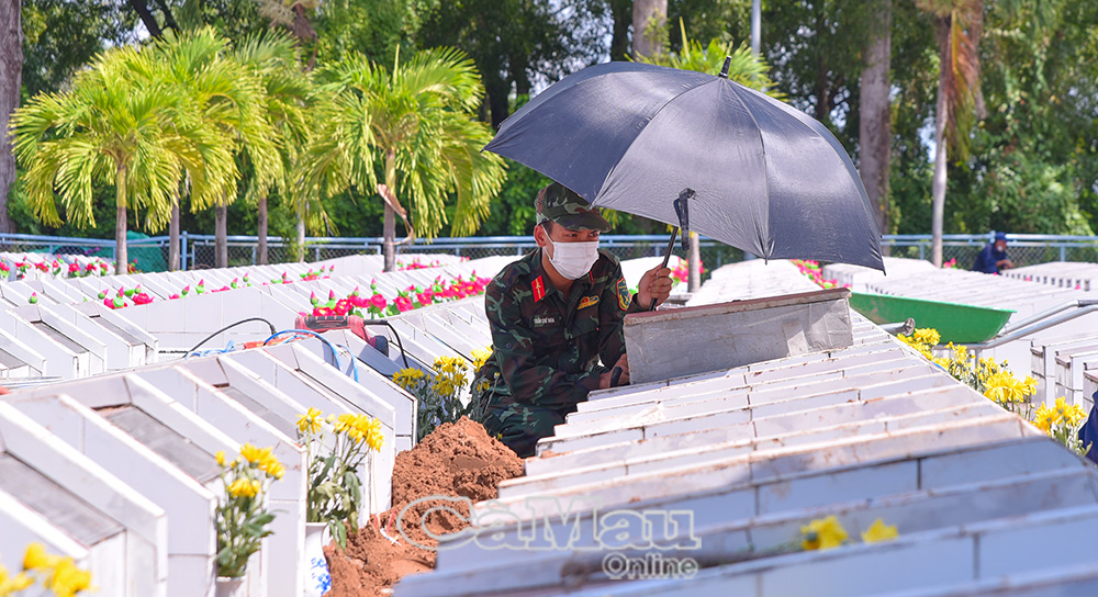 Giữa nghĩa trang, chiến sĩ trẻ cầm chiếc dù nhỏ nghiêng che phần quách vừa lộ diện - hành động giản dị nhưng đong đầy tình cảm của thế hệ hôm nay dành cho thế hệ cha anh.