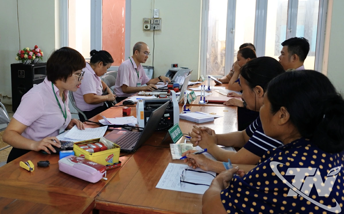 Giao dịch viên Nhân hàng Chính sách xã hội làm việc tại điểm giao dịch xã, hướng dẫn Tổ tiết kiệm và vay vốn thực hiện thủ tục vay.