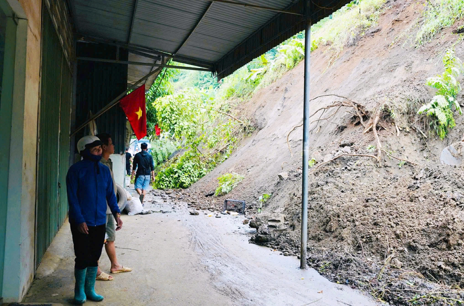 Vị trí sạt lở, đất đá đã tràn qua mặt đường đẩy đất sát đến gần nhà dân sinh sống gần đó.