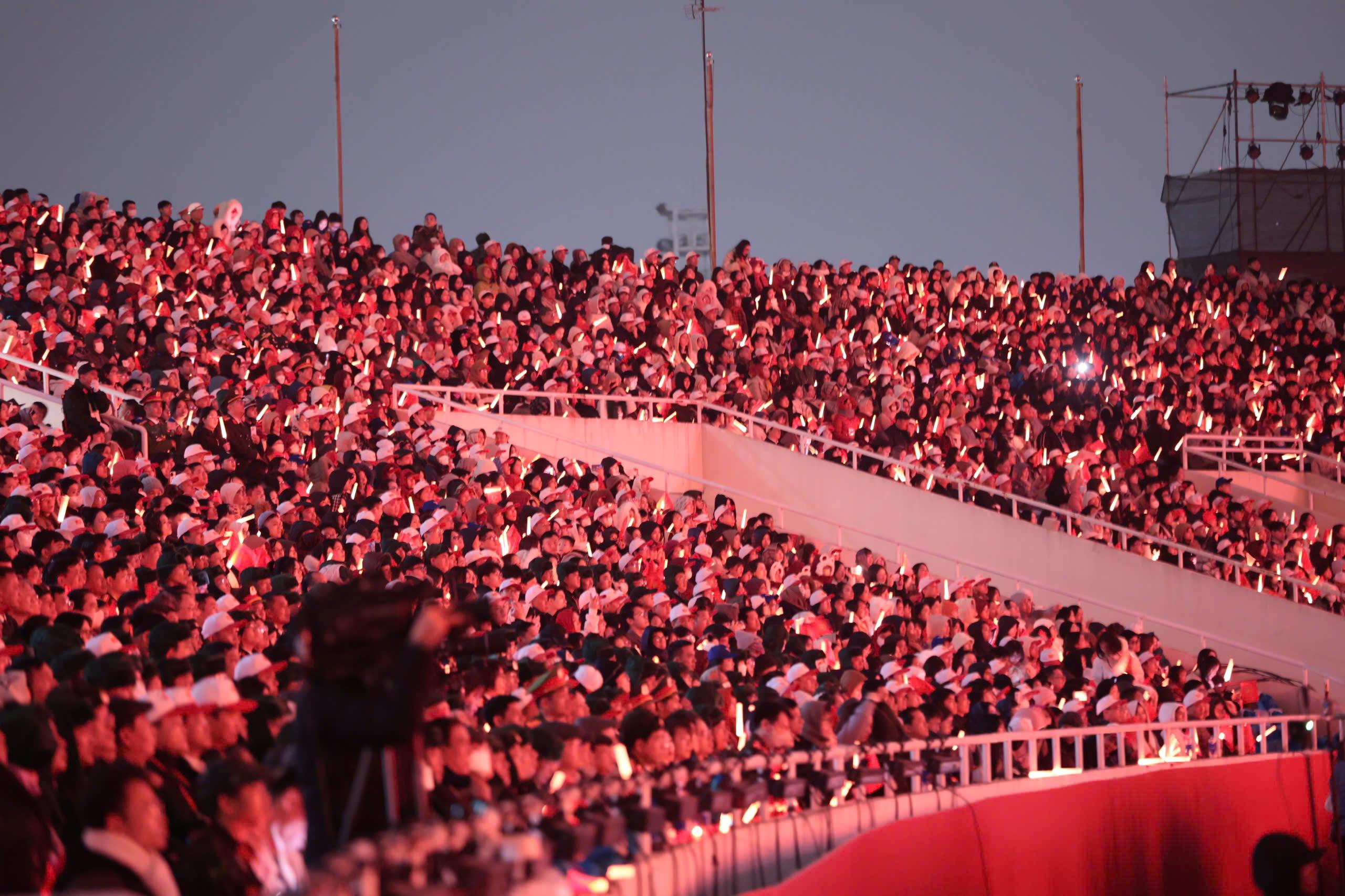 Từ kh&aacute;n đ&agrave;i, kh&aacute;n giả c&oacute; thể cảm nhận sự h&ugrave;ng vĩ khi h&agrave;ng ngh&igrave;n diễn vi&ecirc;n c&ugrave;ng l&uacute;c tạo h&igrave;nh c&aacute;c biểu tượng b&uacute;a liềm, sao v&agrave;ng rực rỡ dưới bầu trời đ&ecirc;m.