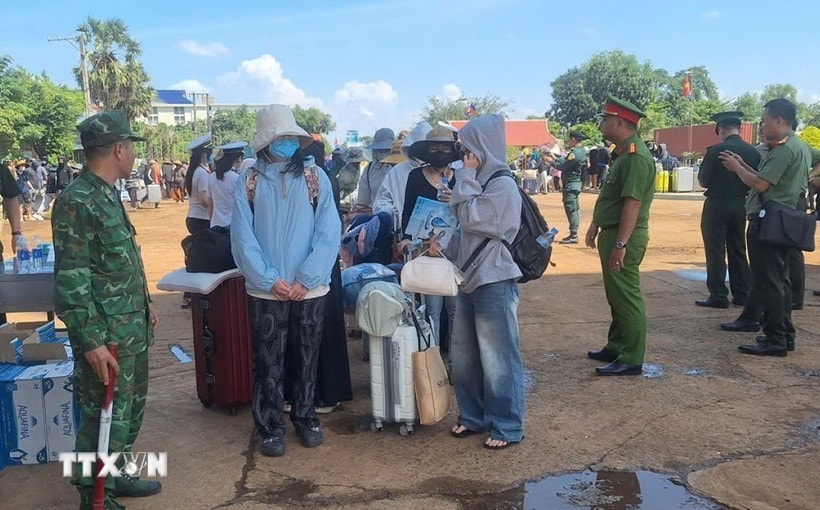 Lực lượng chức năng Việt Nam-Campuchia làm thủ tục bàn giao, tiếp nhận 353 công dân Việt Nam tại Cửa khẩu quốc tế Xa Mát, xã Tân Lập, tỉnh Tây Ninh. (Ảnh: TTXVN phát)