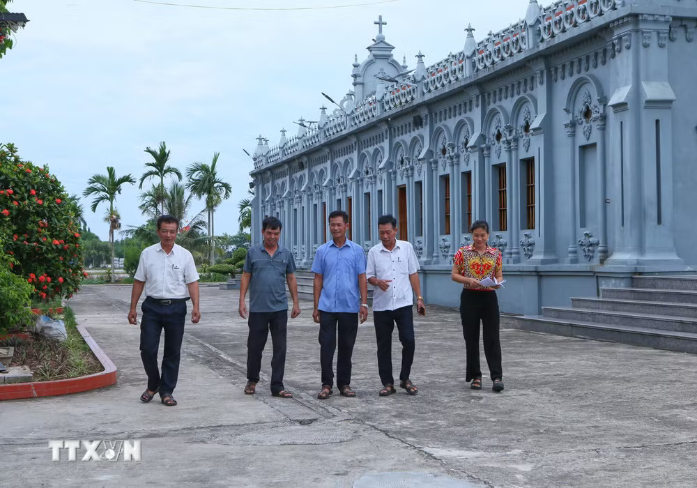Cán bộ xóm 2, xã Nghĩa Sơn tới nhà thờ trên địa bàn để tuyên truyền, vận động người dân đồng thuận với chủ trương sắp xếp, tổ chức lại thôn, tổ dân phố. (Ảnh: Công Luật/TTXVN) ttxvn-cong-giao-ninh-binh-2.jpg