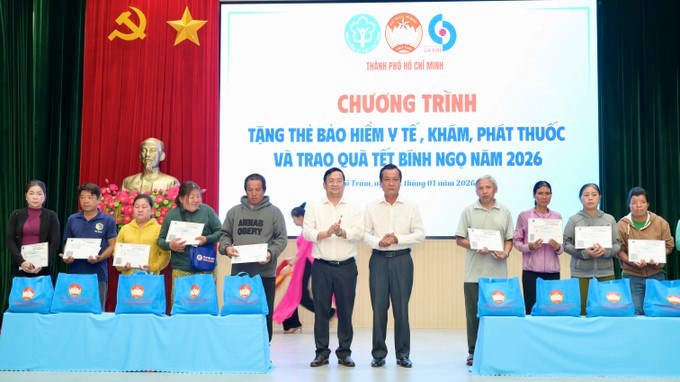 Người d&acirc;n x&atilde; Hồ Tr&agrave;m nhận BHYT v&agrave; qu&agrave;. (Ảnh: SGGP)