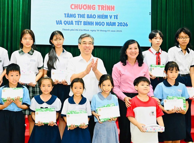 Đồng ch&iacute; Nguyễn Phước Lộc v&agrave; đồng ch&iacute; Huỳnh Thị Kim Xuyến trao qu&agrave; đến c&aacute;c em học sinh. (Ảnh: SGGP)