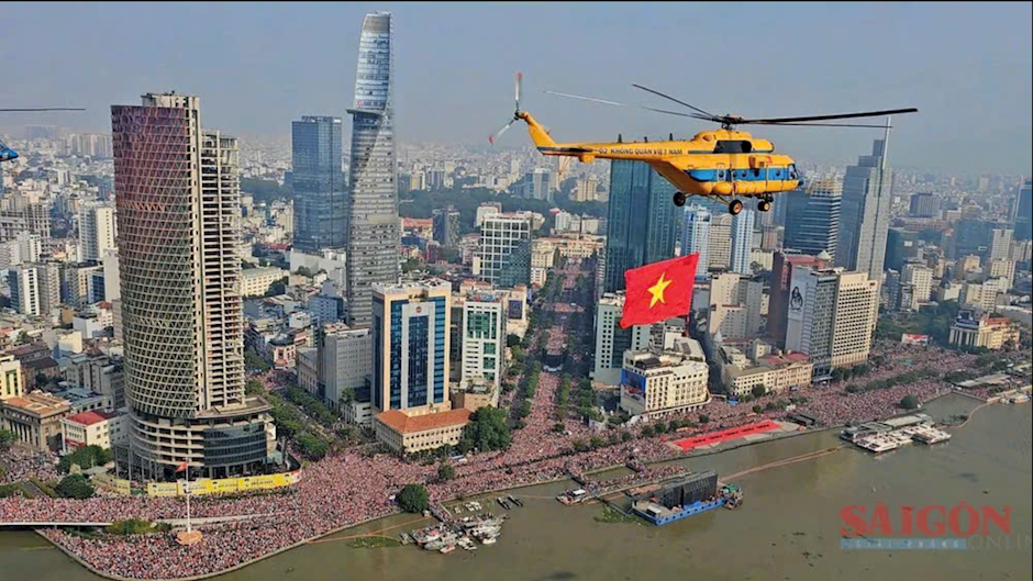 Trực thăng mang cờ Tổ quốc tung bay giữa bầu trời TPHCM, ph&iacute;a dưới h&agrave;ng triệu tr&aacute;i tim hướng về cờ Tổ Quốc. (Ảnh: SGGP)