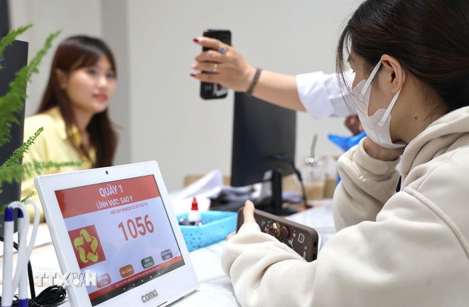 Người dân sử dụng điện thoại thông minh trong quá trình nộp hồ sơ, thủ tục tại Trung tâm phục vụ Hành chính công phường Thủ Đức, Thành phố Hồ Chí Minh. (Ảnh: TTXVN)