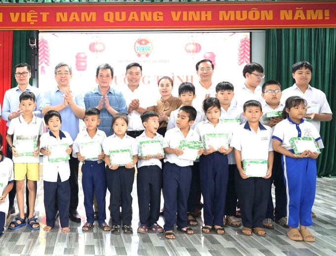 Đồng ch&iacute; Nguyễn Phước Lộc c&ugrave;ng đại diện c&aacute;c đơn vị đồng h&agrave;nh trao qu&agrave; tết đến c&aacute;c em học sinh. (Ảnh: SGGP)