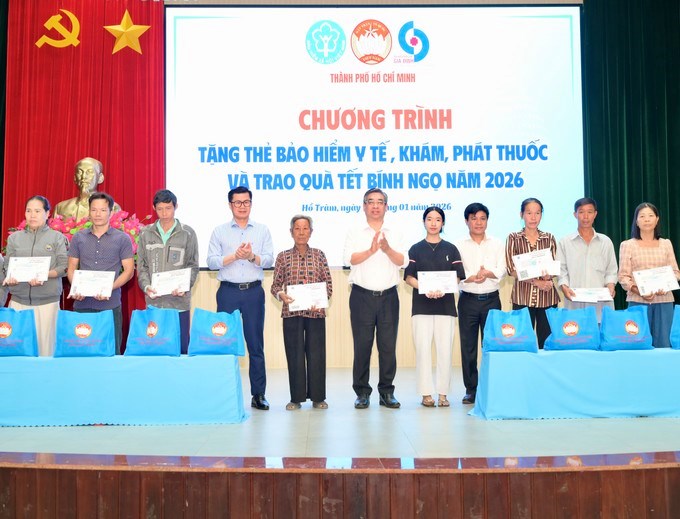 Đồng ch&iacute; Nguyễn Phước Lộc v&agrave; đồng ch&iacute; L&ograve; Qu&acirc;n Hiệp trao thẻ BHYT v&agrave; qu&agrave; đến người d&acirc;n. (Ảnh: SGGP)