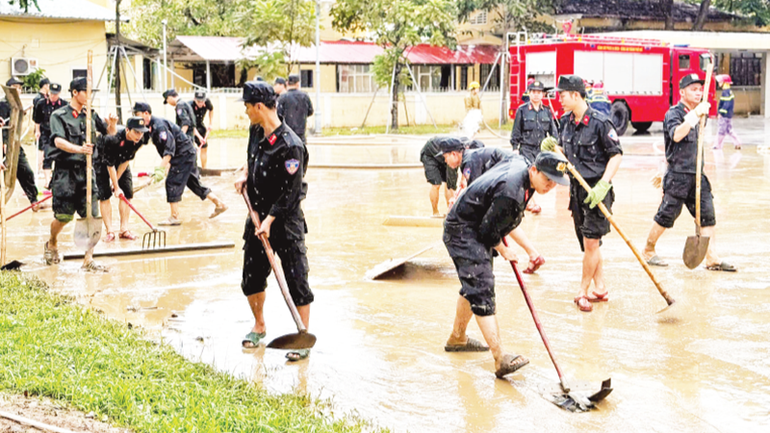 C&aacute;c lực lượng C&ocirc;ng an, qu&acirc;n sự dọn b&ugrave;n sau khi nước lũ r&uacute;t tại th&agrave;nh phố Huế.