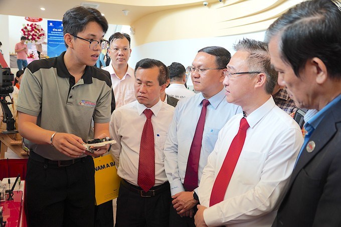 Đồng chí Đặng Minh Thông (thứ 2 từ phải sang) nghe đại diện Trường Đại học Kỹ thuật công nghệ giới thiệu về chip thiết kế vi mạch do trường nghiên cứu, sáng chế. (Ảnh: SGGP)