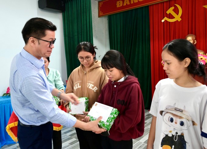 Gi&aacute;m đốc BHXH TPHCM L&ograve; Qu&acirc;n Hiệp trao qu&agrave; đến c&aacute;c em học sinh. (Ảnh: SGGP)