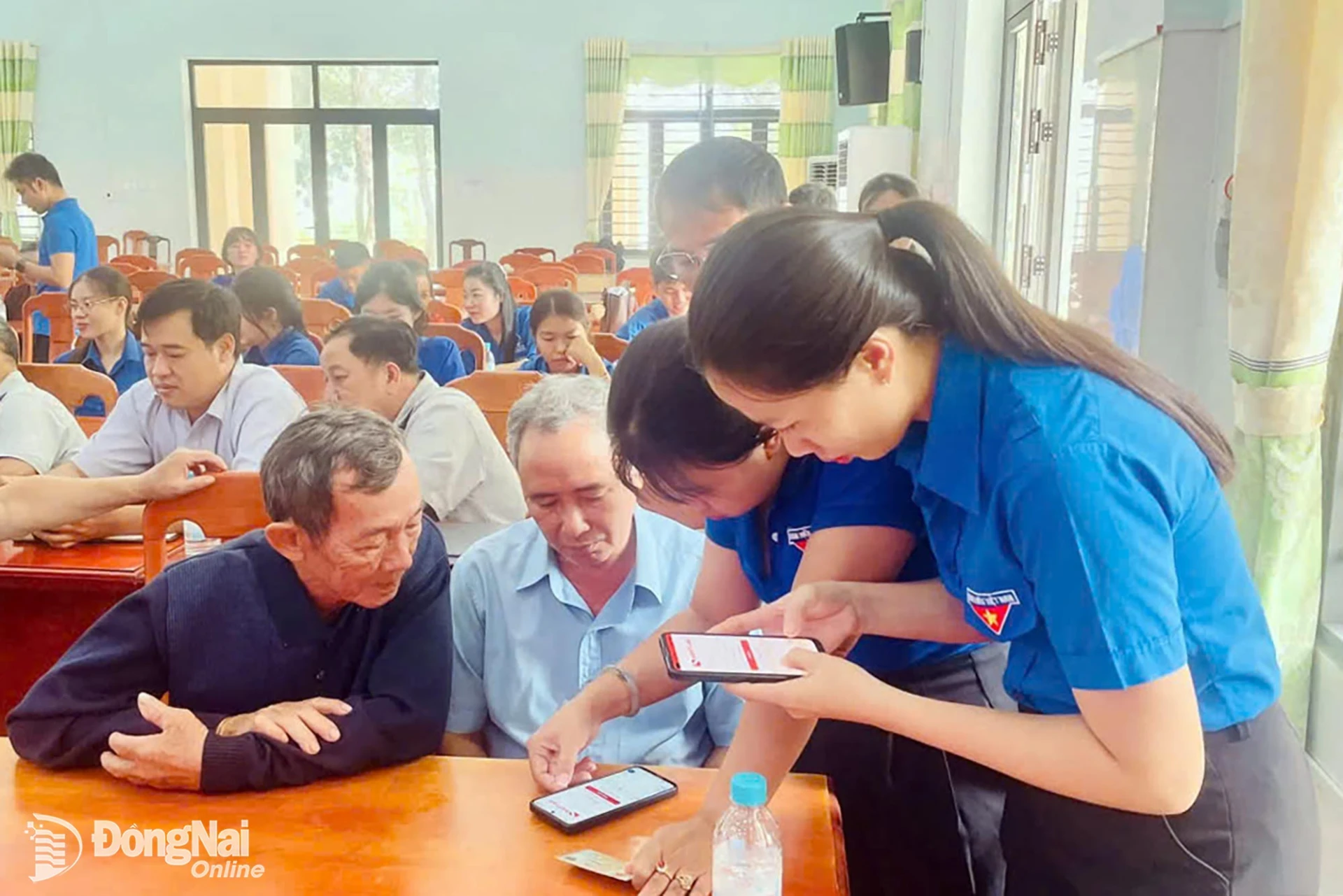 Đoàn viên thanh niên xã Đồng Tâm hướng dẫn, hỗ trợ người cao tuổi cài đặt ứng dụng học trực tuyến Bình dân học vụ số. Ảnh: ĐVCC
