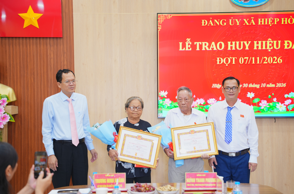 Tỉnh ủy viên, Phó Bí thư chuyên trách Đảng ủy các cơ quan Đảng tỉnh Huỳnh Thanh Phương, cùng Bí thư Đảng ủy, Chủ tịch HĐND xã Trương Minh Khánh trao Huy hiệu 60 năm tuổi đảng cho đảng viên Hoàng Bâm và đảng viên Đặng Ngọc Minh