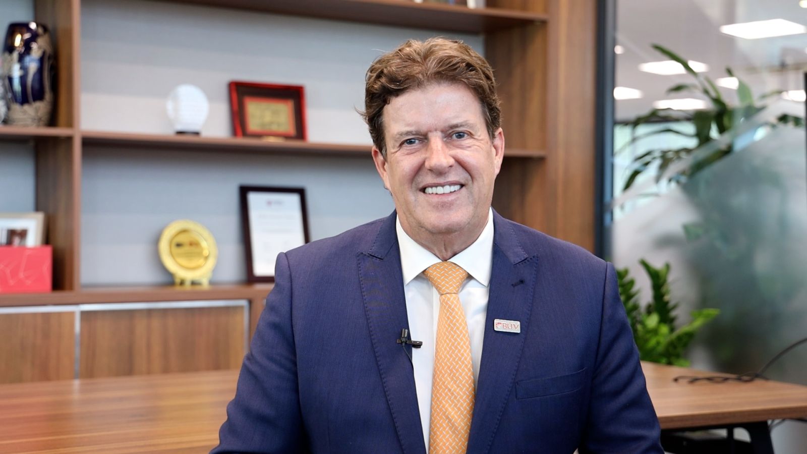 A person in a suit smiling  Description automatically generated
