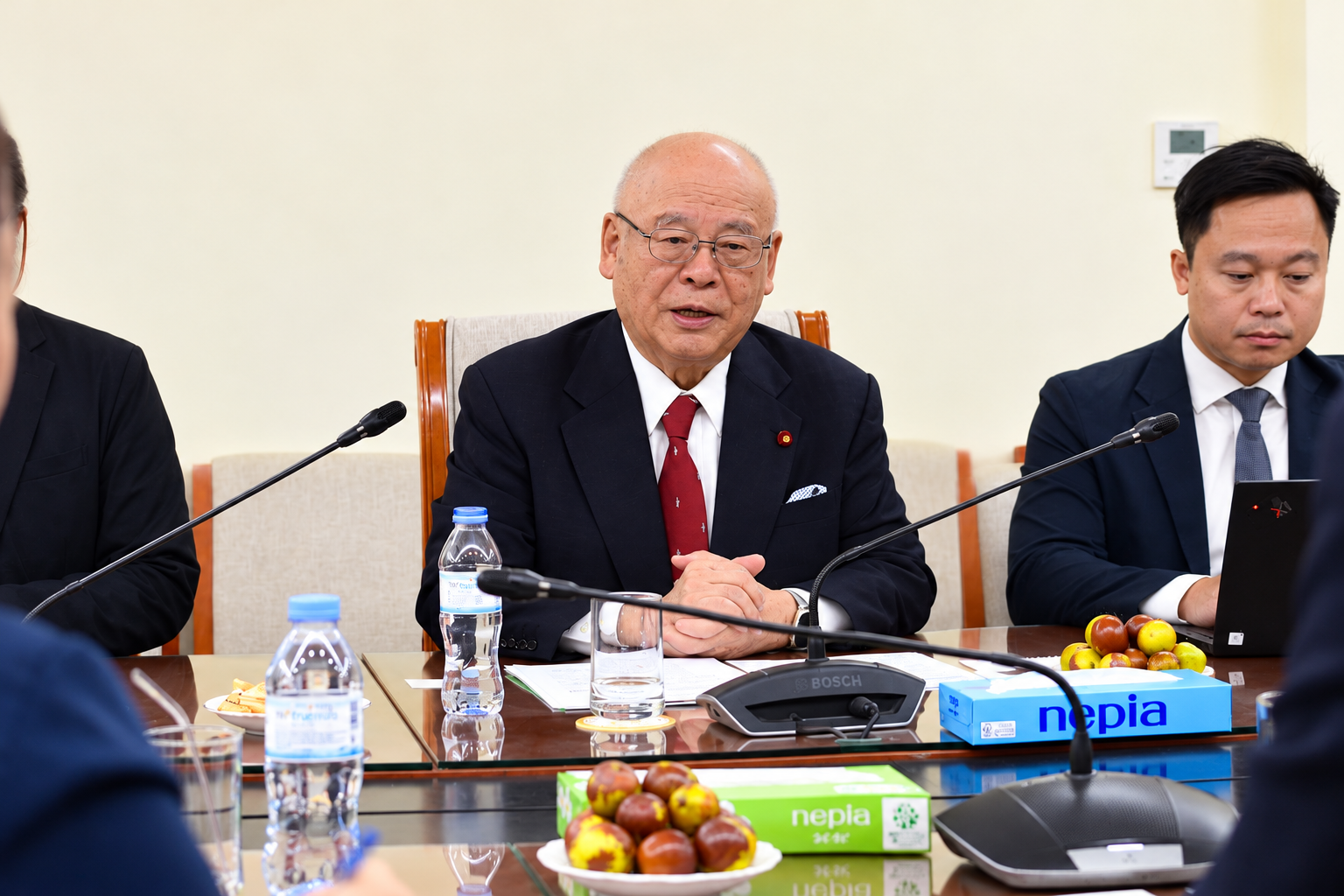 A group of men sitting at a table with microphones  Description automatically generated